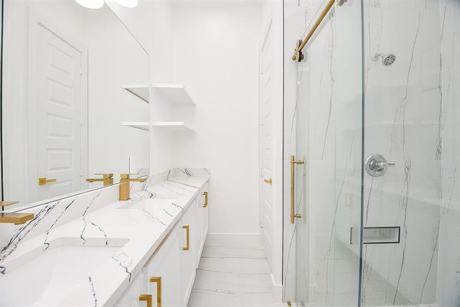 This exquisite ensuite offers a spa-like retreat, featuring dual sinks on a gleaming quartz countertop and an oversized glass shower. Elegant gold accents and sleek finishes complete this sophisticated primary bath.