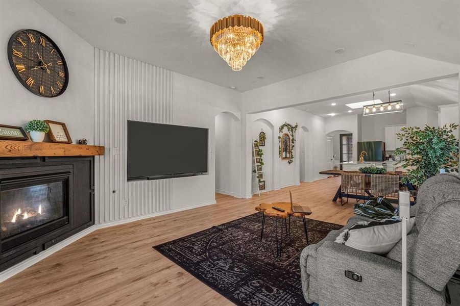 Living room featuring hardwood / wood-style flooring, an inviting chandelier, and vaulted ceiling