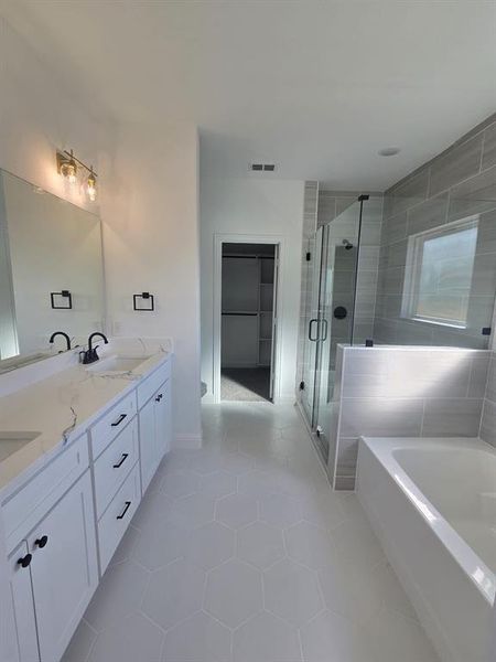 Full bathroom featuring double vanity, light tile patterned floors, a garden tub, and a stall shower