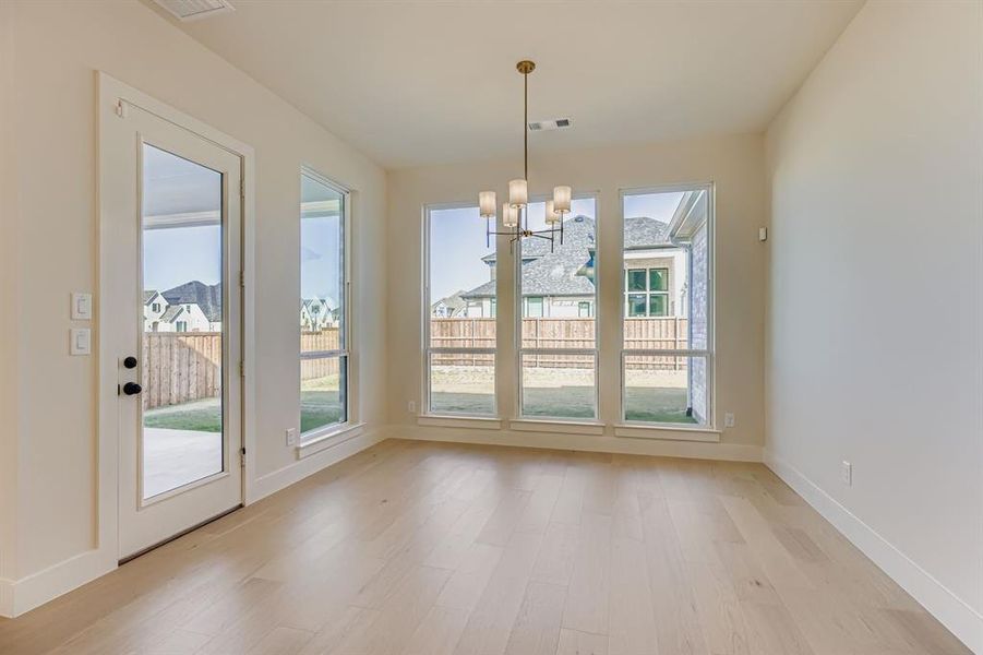 Unfurnished dining area with light wood-type flooring, healthy amount of natural light, and a chandelier