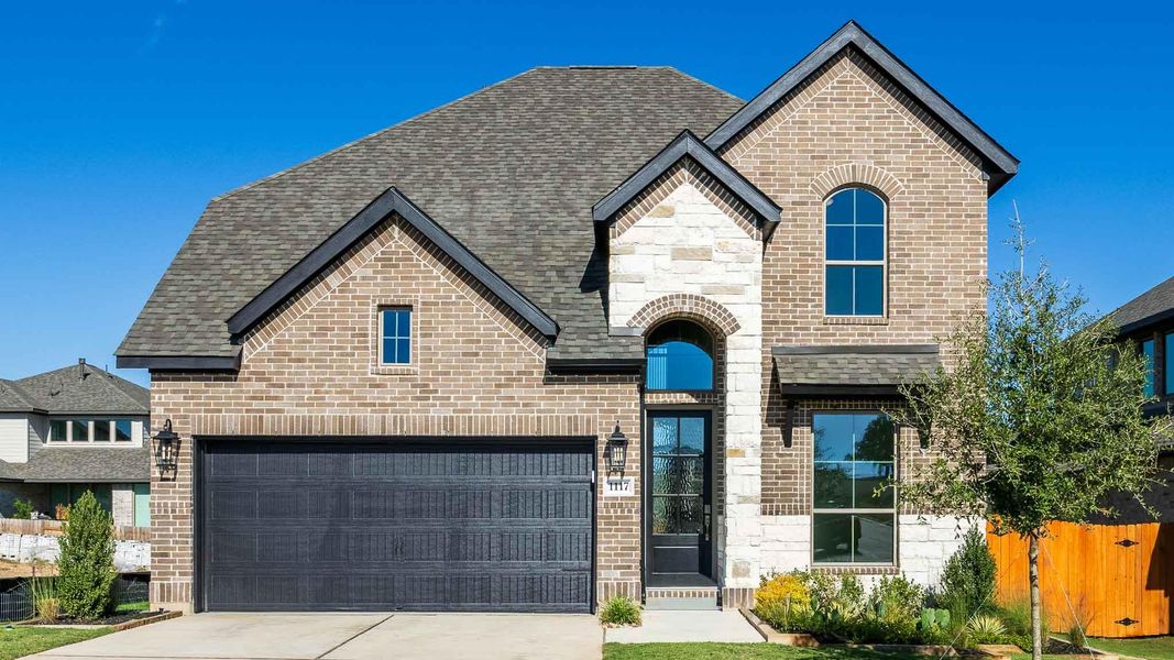 French country inspired facade featuring brick siding, stone siding, driveway, and a shingled roof French country inspired facade featuring brick siding, stone siding, driveway, and a shingled roof