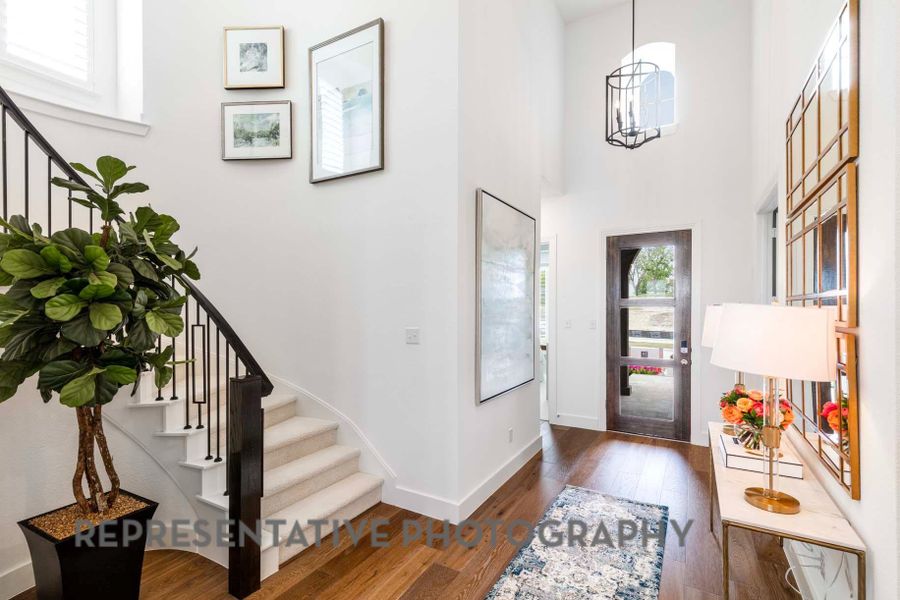 Foyer entrance with stairs, a towering ceiling, baseboards, and hardwood / wood-style floors Foyer entrance with stairs, a towering ceiling, baseboards, and hardwood / wood-style floors