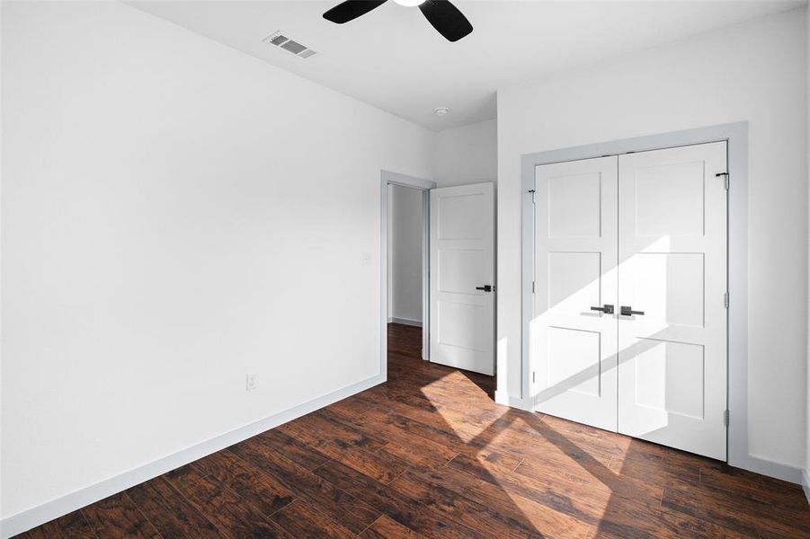Unfurnished bedroom featuring a closet, dark wood finished floors, and a ceiling fan