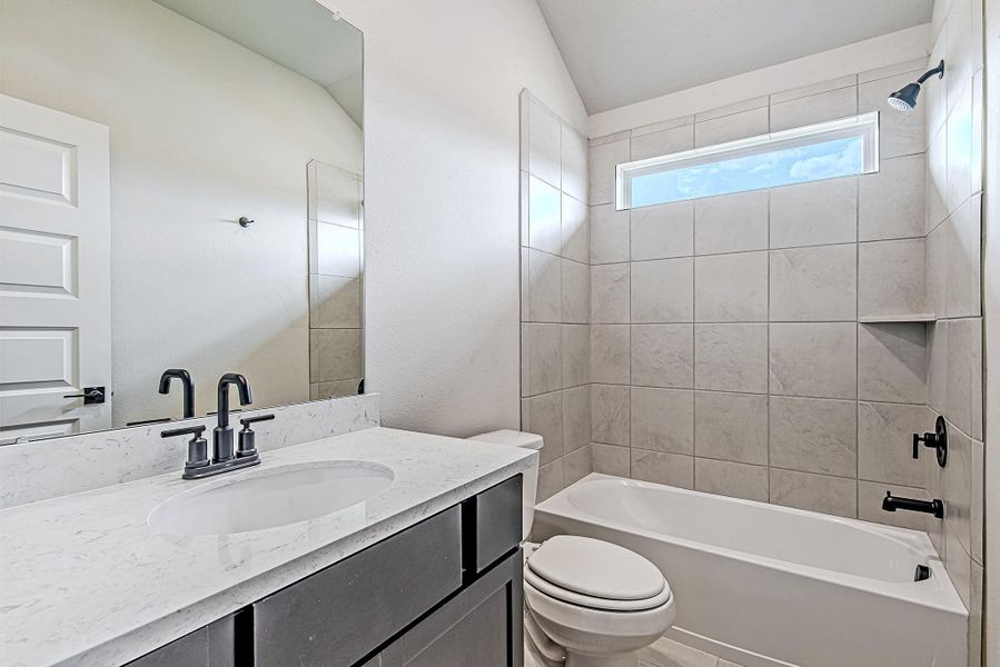 Upstairs bathroom with soft neutral tile, quartz countertops, and stylish black hardware—perfectly placed between secondary bedrooms.