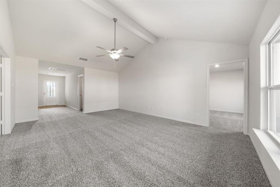 Carpeted empty room with plenty of natural light, lofted ceiling with beams, and ceiling fan