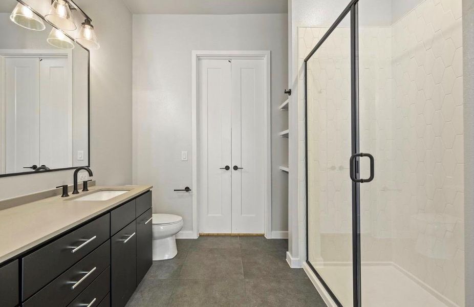 Dark cabinetry and a glass-enclosed shower highlight this modern, tiled bathroom. Dark cabinetry and a glass-enclosed shower highlight this modern, tiled bathroom.