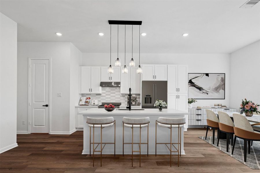 Virtually staged kitchen with sleek modern finishes, styled with dining table and accents to highlight the open-concept design.