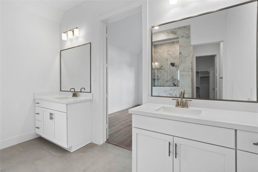 Modern primary bath features dual vanities with sleek cabinetry, quartz countertop, and brushed nickel fixtures for a truly contemporary feel.