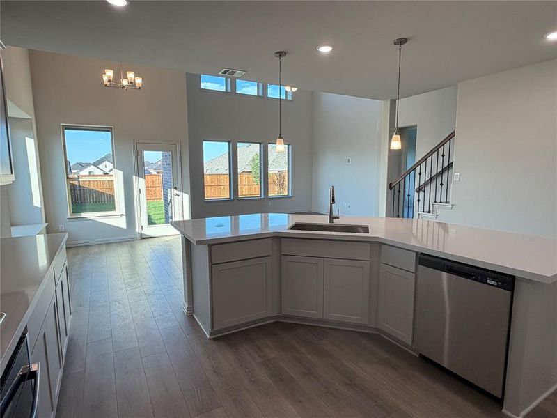 Open-concept kitchen and living area featuring wood-finish flooring, white cabinetry, and light-toned countertops Open-concept kitchen and living area featuring wood-finish flooring, white cabinetry, and light-toned countertops