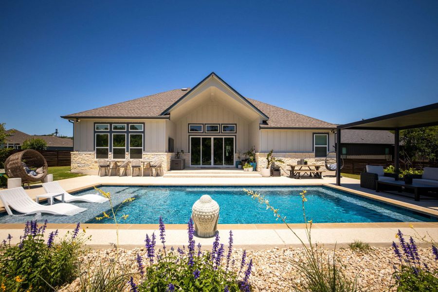 A tranquil backyard oasis boasts a sparkling in-ground pool and multiple seating areas perfect for unwinding.