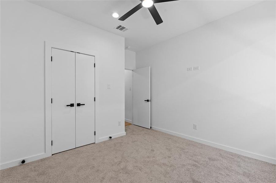 Unfurnished bedroom with carpet, a closet, and a ceiling fan Unfurnished bedroom with carpet, a closet, and a ceiling fan