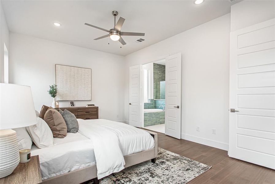 Bedroom with dark hardwood / wood-style flooring, ensuite bath, and ceiling fan