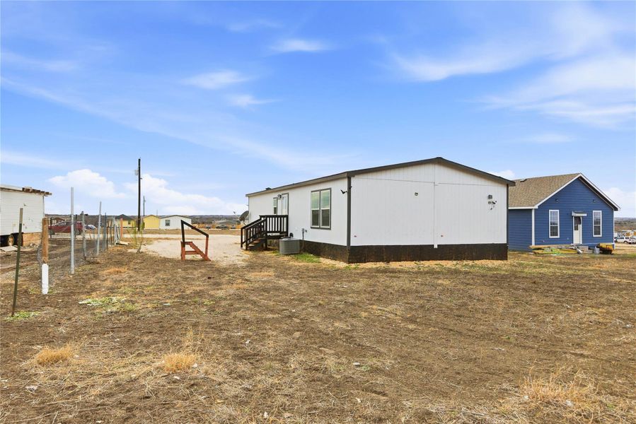 A manufactured home with white siding and dark trim offers straightforward living on a spacious, open lot.