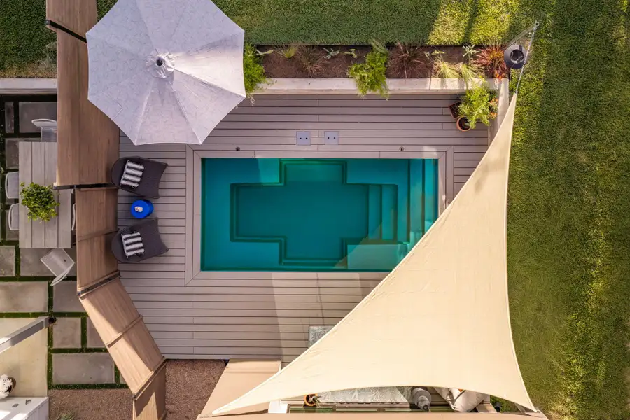 An aerial perspective captures a sparkling blue swimming pool framed by modern decking. An aerial perspective captures a sparkling blue swimming pool framed by modern decking.
