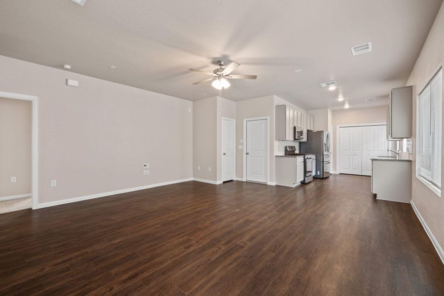 Unfurnished living room with dark wood-type flooring and a ceiling fan