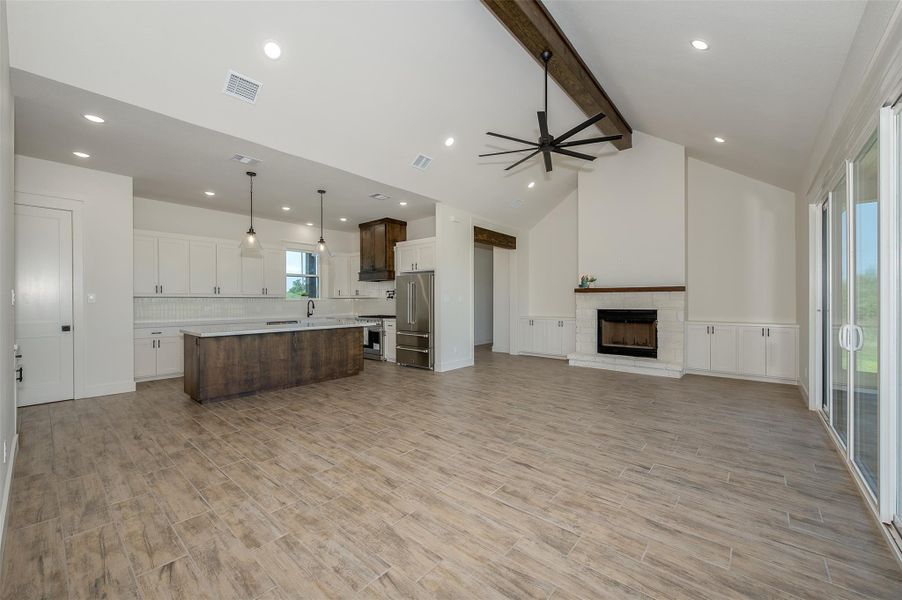 Kitchen featuring open floor plan, wainscoting, beamed ceiling, a decorative wall, and ceiling fan
