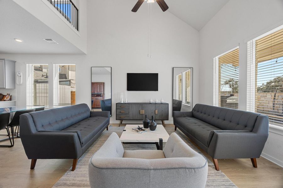 Living room featuring light luxury vinyl finished floors, ceiling fan, and high vaulted ceiling