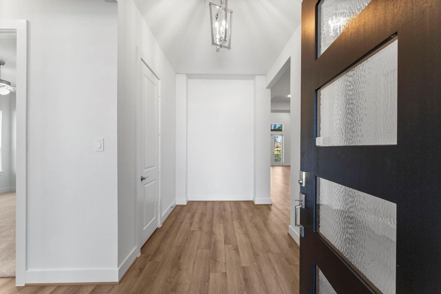 Welcoming entry with a modern glass-paneled front door and chandelier. Welcoming entry with a modern glass-paneled front door and chandelier.