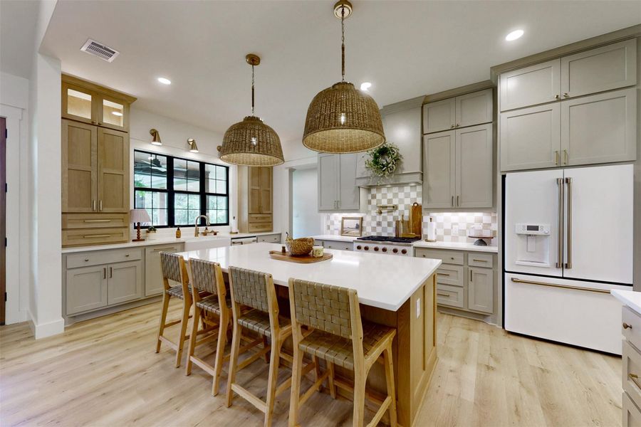 Kitchen with white fridge with ice dispenser, light wood-type flooring, light countertops, decorative backsplash, and gray cabinets