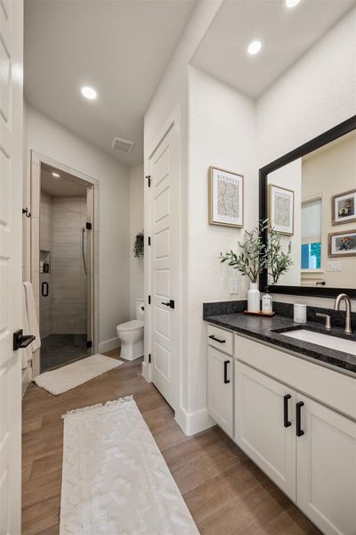 Bathroom featuring hardwood / wood-style flooring, vanity, a shower with door, and toilet Bathroom featuring hardwood / wood-style flooring, vanity, a shower with door, and toilet