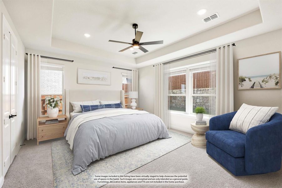 Bedroom with tray ceiling, ceiling fan, carpet, blue armchair, and two windows with white curtains