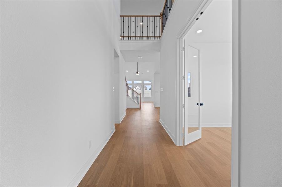 Corridor featuring a high ceiling, light wood-type flooring, and a barn door