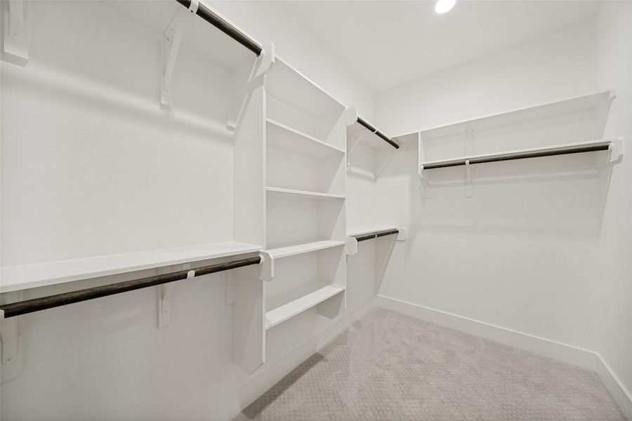 Ample storage solutions await in this naturally illuminated walk-in closet with built-in shelving and hanging rods. Ample storage solutions await in this naturally illuminated walk-in closet with built-in shelving and hanging rods.