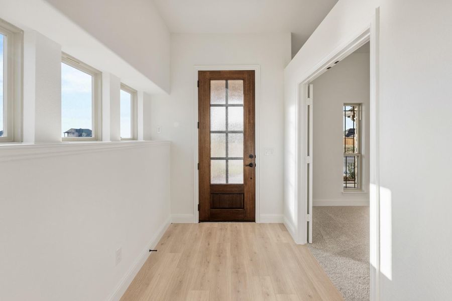Entryway with wood and glass front door, white walls, and light hardwood floors Entryway with wood and glass front door, white walls, and light hardwood floors
