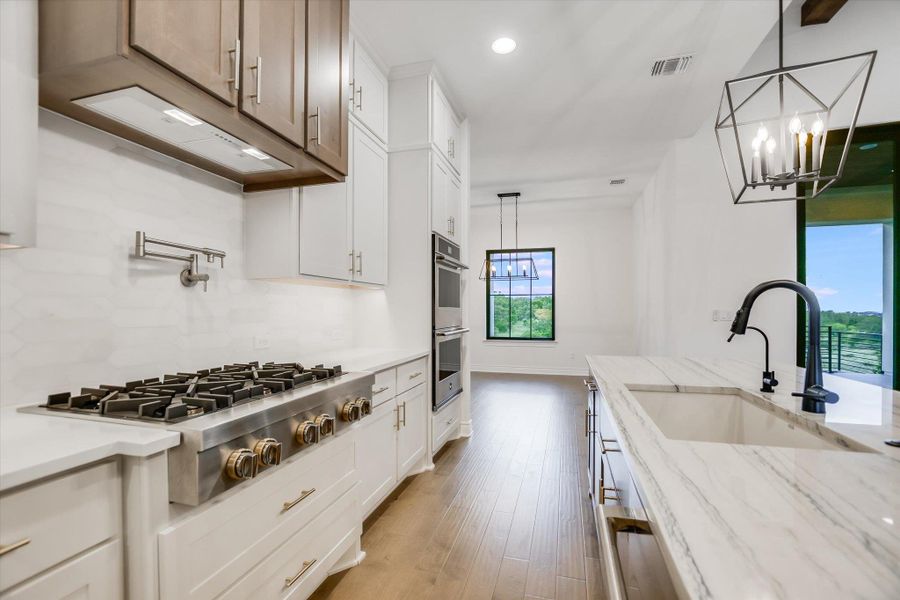 Kitchen with appliances with stainless steel finishes, recessed lighting, a chandelier, light wood-style flooring, and white cabinets