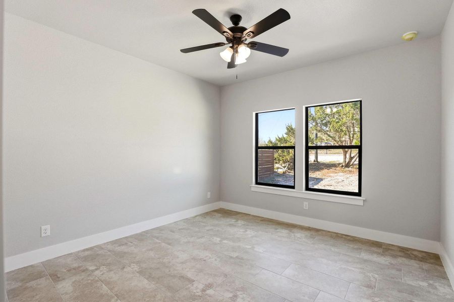 A well-lit bedroom with durable tile flooring and a refreshing ceiling fan. A well-lit bedroom with durable tile flooring and a refreshing ceiling fan.