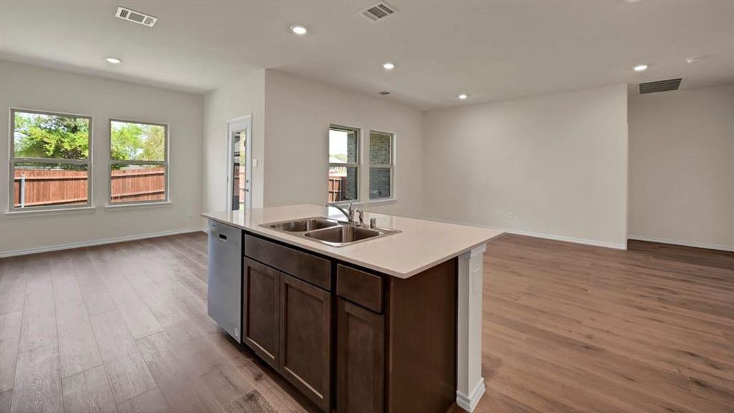 Central island featuring a dual basin sink, light-toned countertop, and dark wood-finish cabinetry