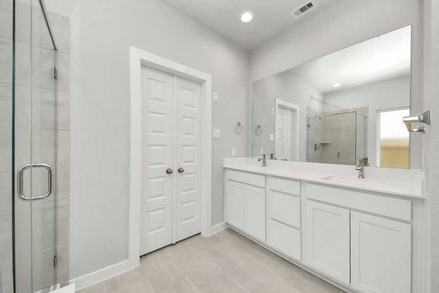 Elevate your daily routine at the elegant vanity, now equipped with double sinks, light countertops, modern hardware, and beautiful recessed lights.