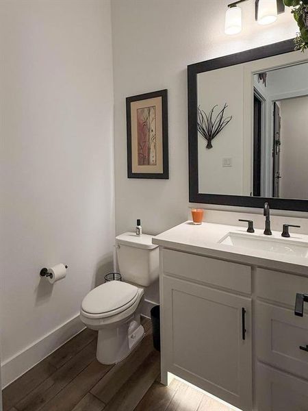 Half bathroom featuring vanity and dark wood-style floors Half bathroom featuring vanity and dark wood-style floors