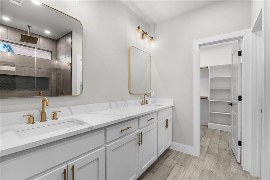 Full bath featuring double vanity, wood finished floors, a stall shower, and a sink