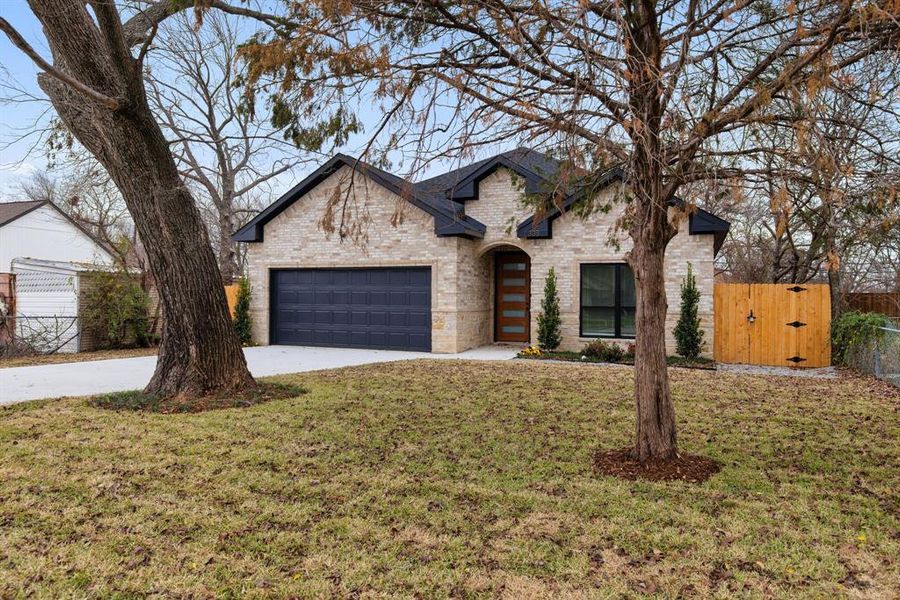 View of front facade featuring a garage and a front lawn