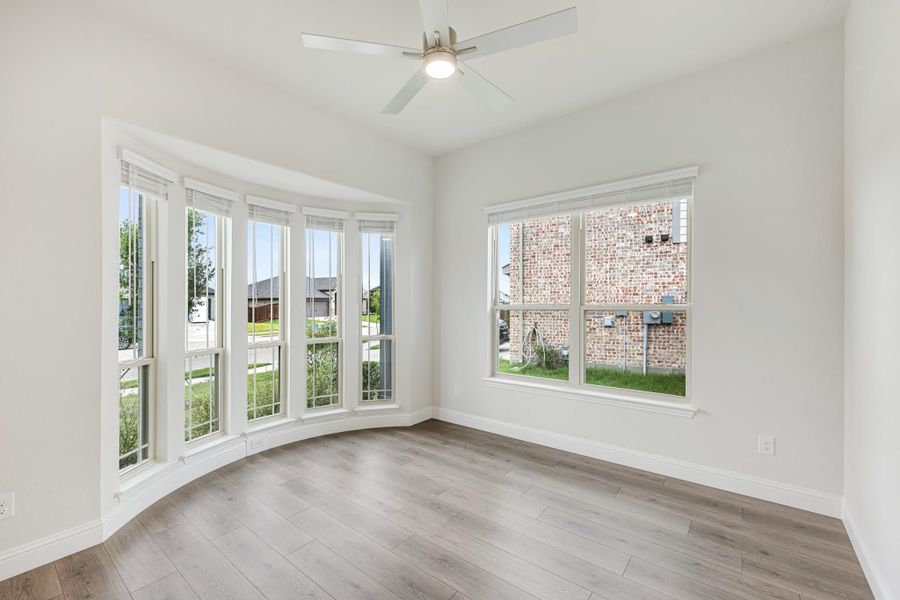 Empty room with hardwood floors, ceiling fan, and large bay windows with natural light Empty room with hardwood floors, ceiling fan, and large bay windows with natural light