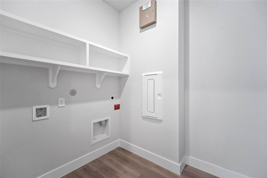 This bright and functional laundry room is conveniently located and ready for your appliances. It features clean white walls, trim, and shelving.