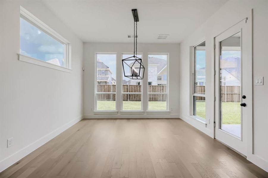 Room featuring wood-finish flooring, white baseboards, and a modern geometric chandelier Room featuring wood-finish flooring, white baseboards, and a modern geometric chandelier