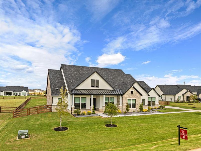 Modern farmhouse featuring a standing seam roof, a metal roof, covered porch, stone siding, and a residential view