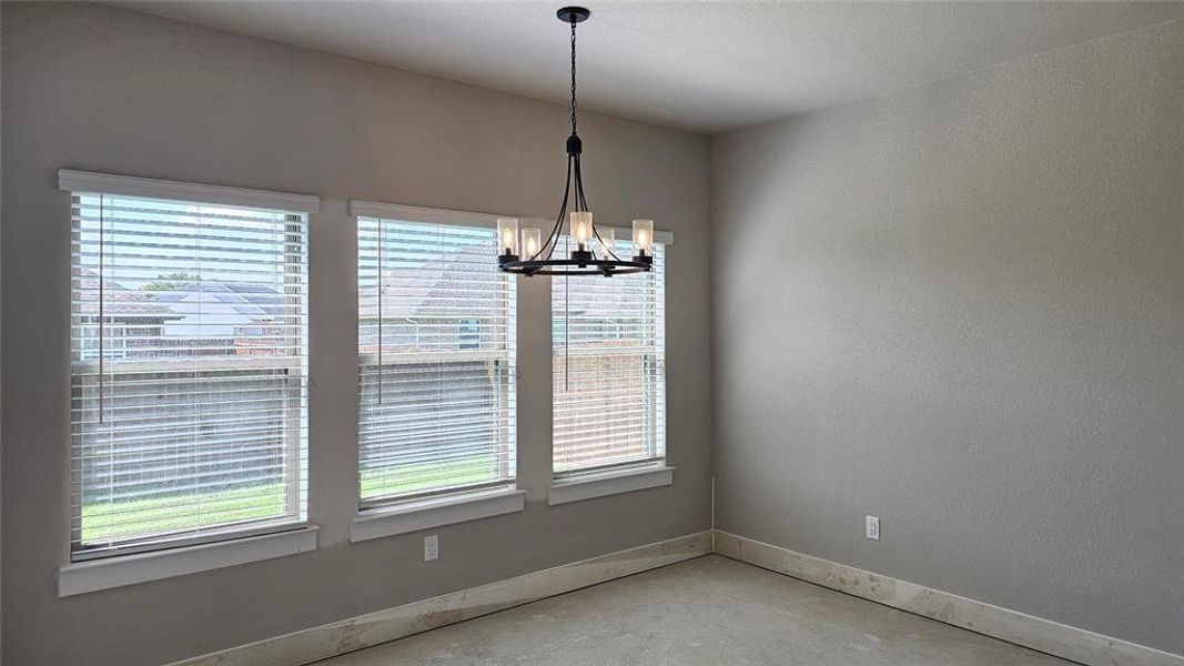 Unfurnished dining area with a chandelier and concrete flooring