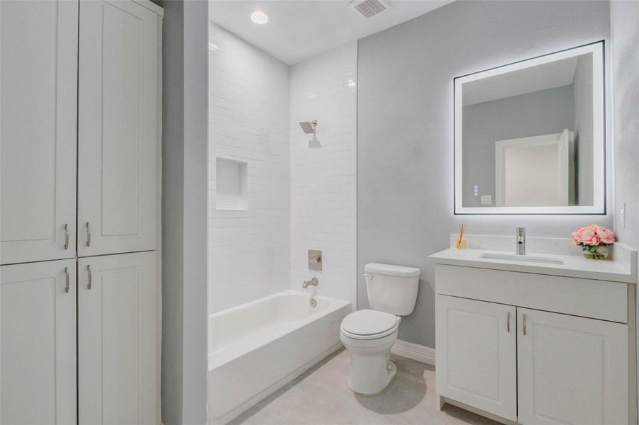 Beautiful secondary bathroom offering an LED-lit mirror, custom built-in cabinet, and clean, contemporary finishes