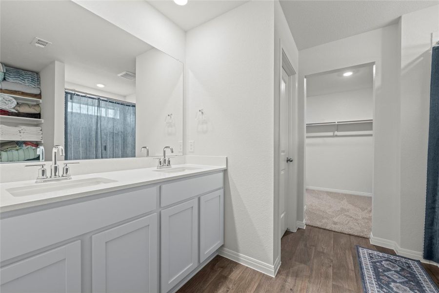 Double vanities with sleek chrome fixtures anchor this well-appointed bathroom, offering ample space and convenience.