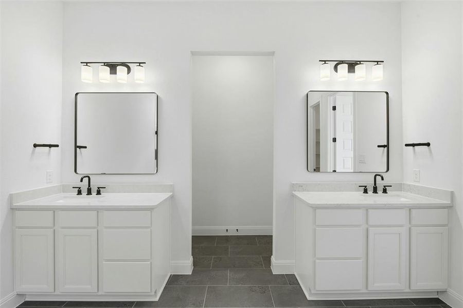 Dual white vanities with integrated sinks, light-toned countertops, and matte black fixtures