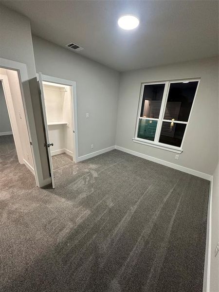 Unfurnished bedroom with a spacious closet, a closet, and carpet floors