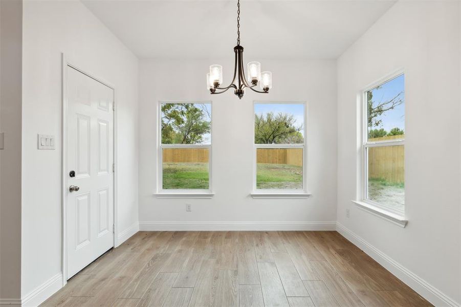 Unfurnished dining area featuring light wood-type flooring and a notable chandelier