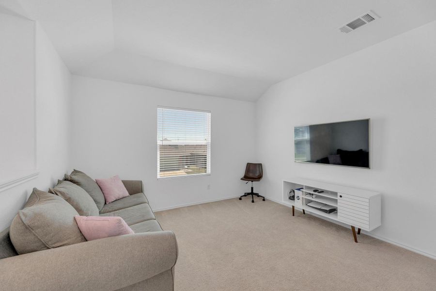 Living room with visible vents, light colored carpet, baseboards, and lofted ceiling