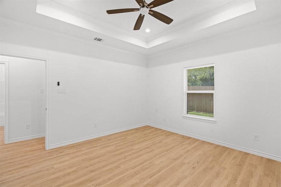 Spare room featuring a raised ceiling, ornamental molding, light wood-style flooring, a ceiling fan, and recessed lighting Spare room featuring a raised ceiling, ornamental molding, light wood-style flooring, a ceiling fan, and recessed lighting