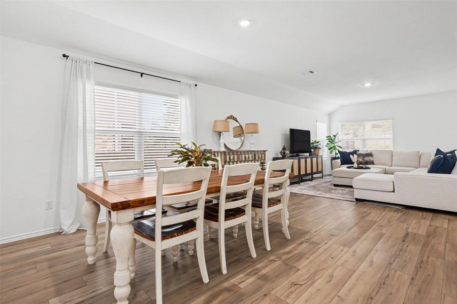 Open-concept living area featuring wood-finish flooring, recessed lighting, white walls, and a large window with blinds