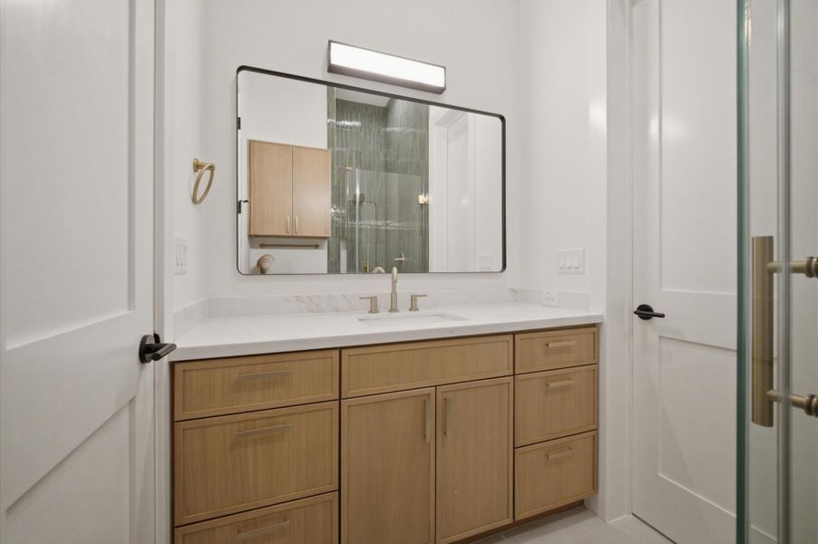 Bathroom vanity with quartz countertops and white oak cabinetry.