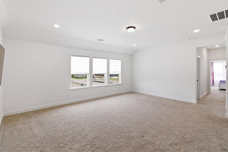 Spacious room featuring neutral carpet flooring, three windows with blinds, recessed ceiling lighting, and a semi-flush mount light fixture